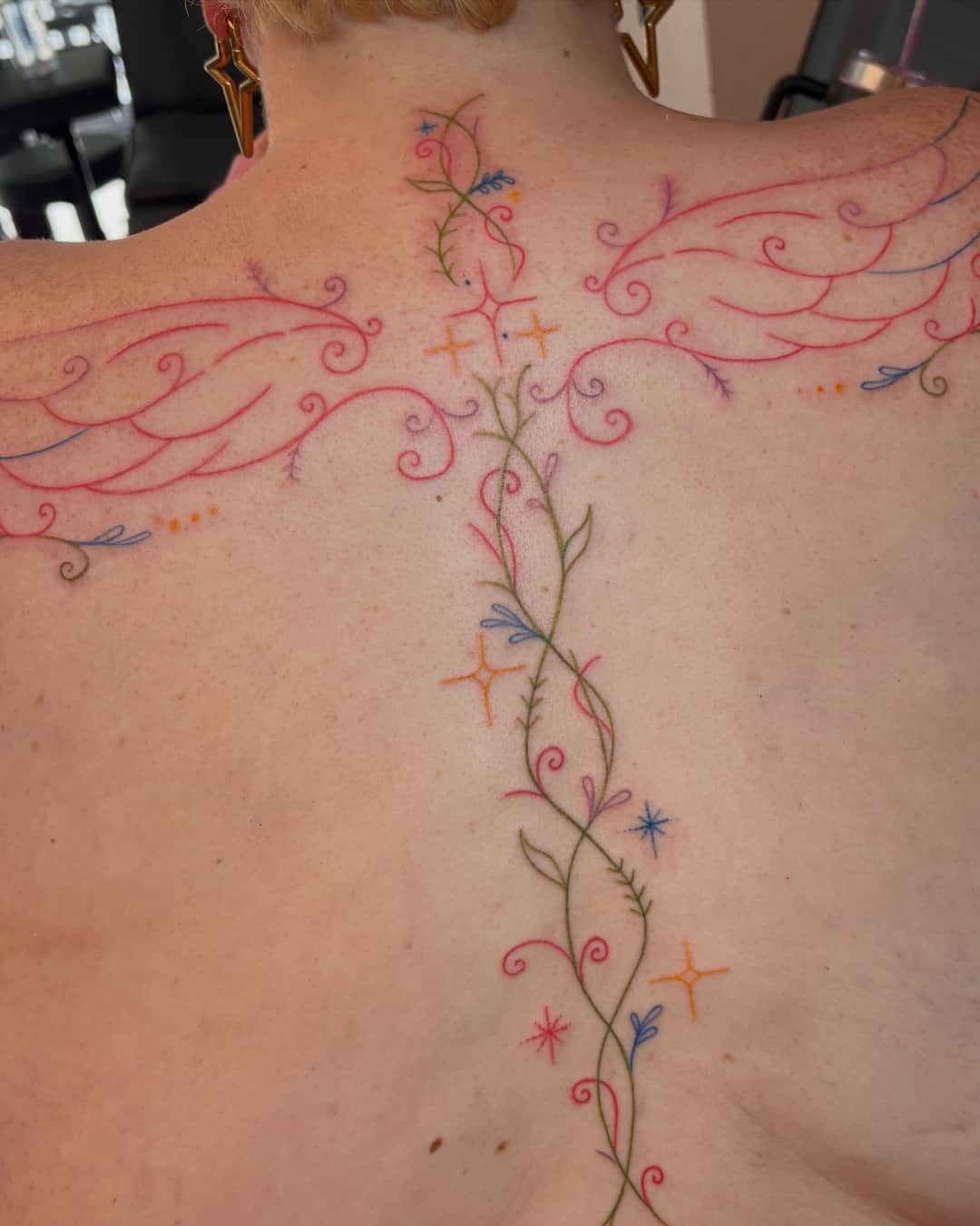 Star, wing, leaf and vine tattoo on the spine, Ornamental style, by Emma in Austin, TX